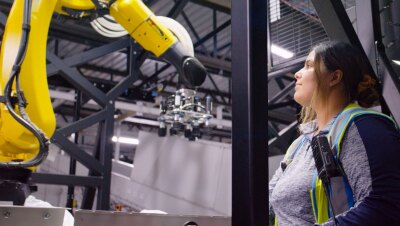 An Amazon employee looks up at a robotic system in a fulfillment center.