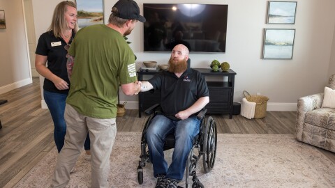 A photo of Matthew Williams, senior program manager on Amazon’s Global Military Affairs team, shaking hands with a U.S. veteran in a wheelchair in their home.