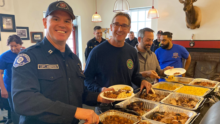 A photo of a firefighters from the Seattle Fire Department serving food on their plates from a buffet.