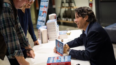 Author Robert Dugoni signs a copy of his book for a fan, looking up at the fan and engaging in conversation.