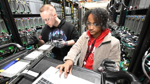 A photo of two data center technicians inspecting hardware inside an AWS Data Center. 