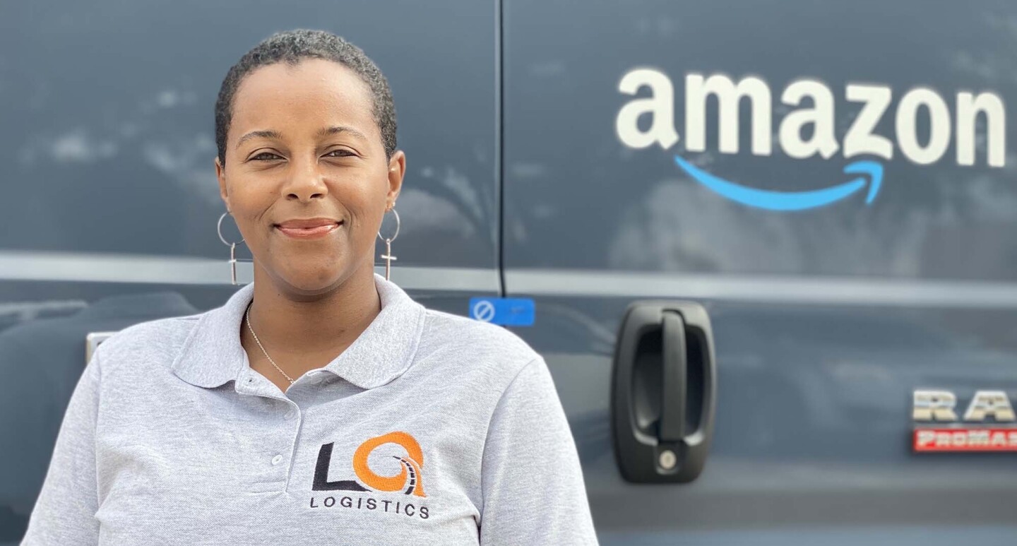 Amazon Delivery Service Partner Quanique Toston stands in front of an Amazon delivery van. 