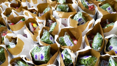 Overhead photograph of dozens of bags filled with fresh strawberries, spinach, and other groceries.