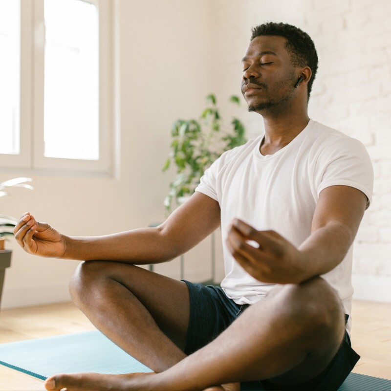A man sits cross-legged closing his eyes and meditating.