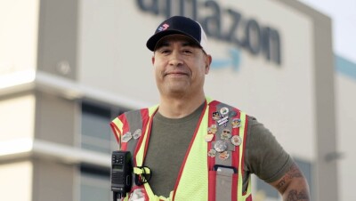 A photo of Norbie Lara, Assistant Site Leader, standing in front of a Fulfillment Center in Fresno, California. 