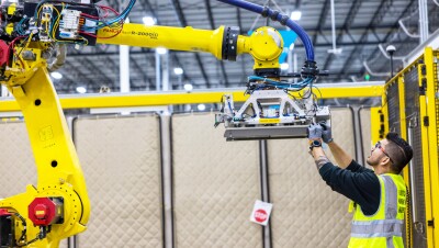 A photo of an Amazon employee working on a robot in a warehouse. 