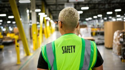 A person wearing a safety vest in a warehouse.