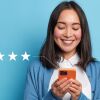 Five-star review concept with smiling woman holding orange smartphone