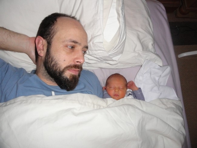 concerned dad in bed with newborn baby