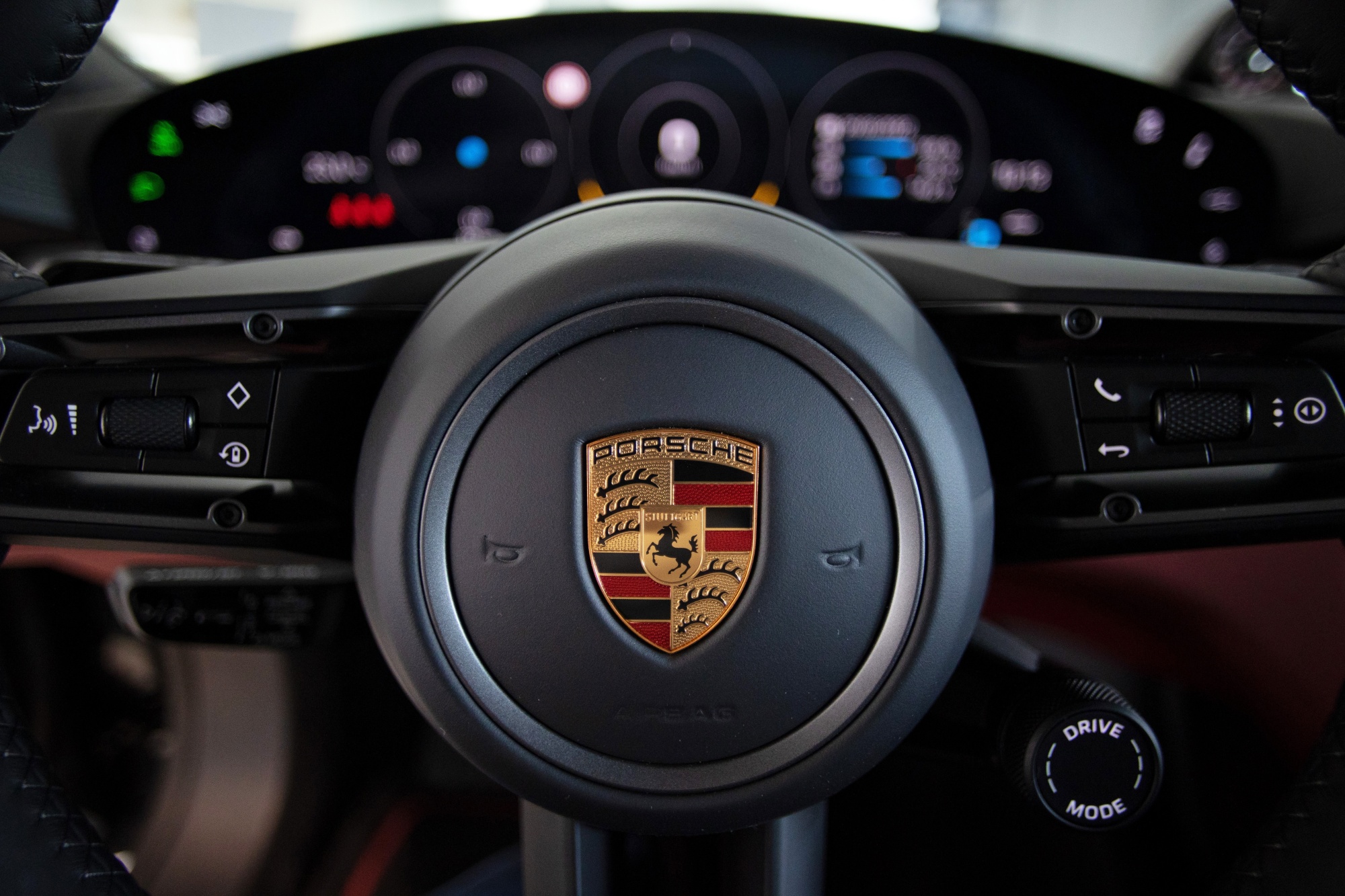 The Porsche logo on the steering wheel of a Taycan 4S electric vehicle.