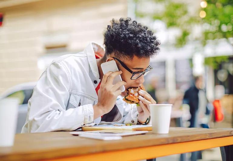 man eating while talking on phone