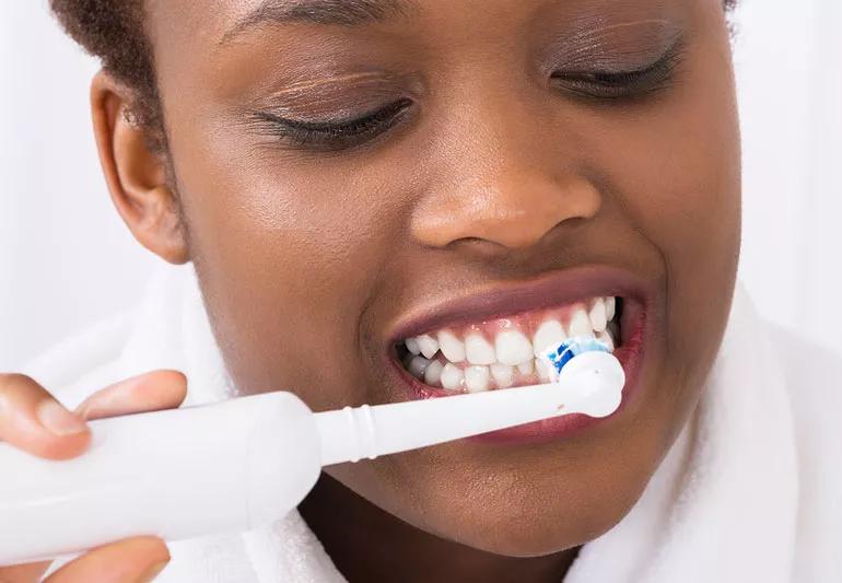 Person brushing their teeth with an electric toothbrush.