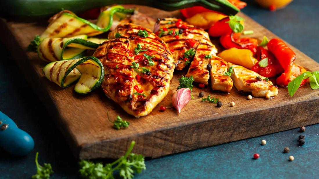 Grilled chicken with summer vegetables on cutting board