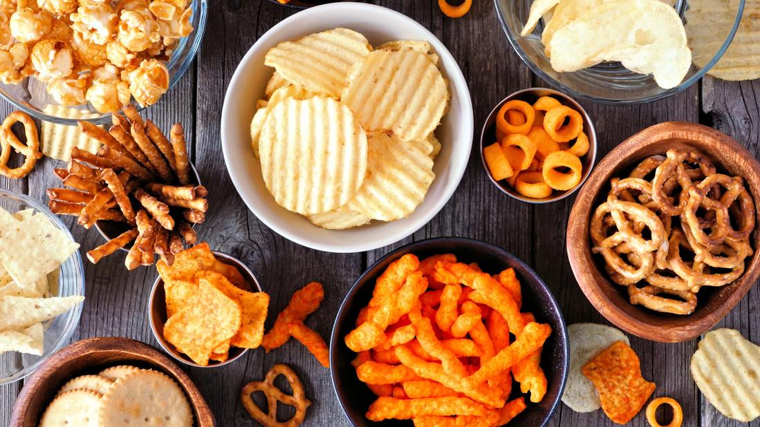 Bowls of processed snacks, potato chips, carmel corn, pretzels, cheese puffs