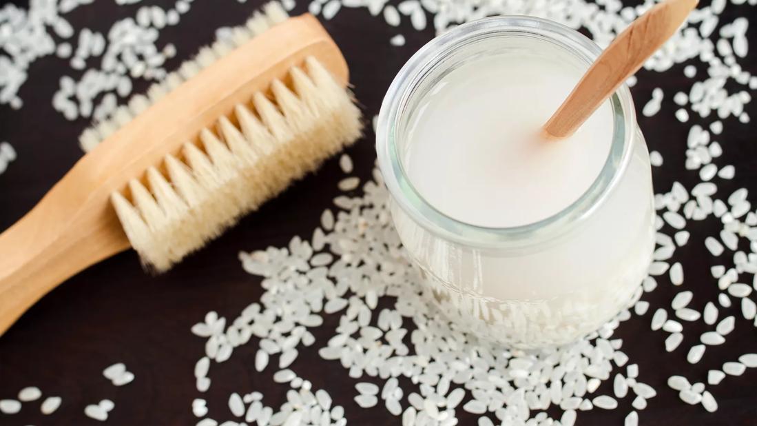 jar of rice water and brush, with rice scattered around table