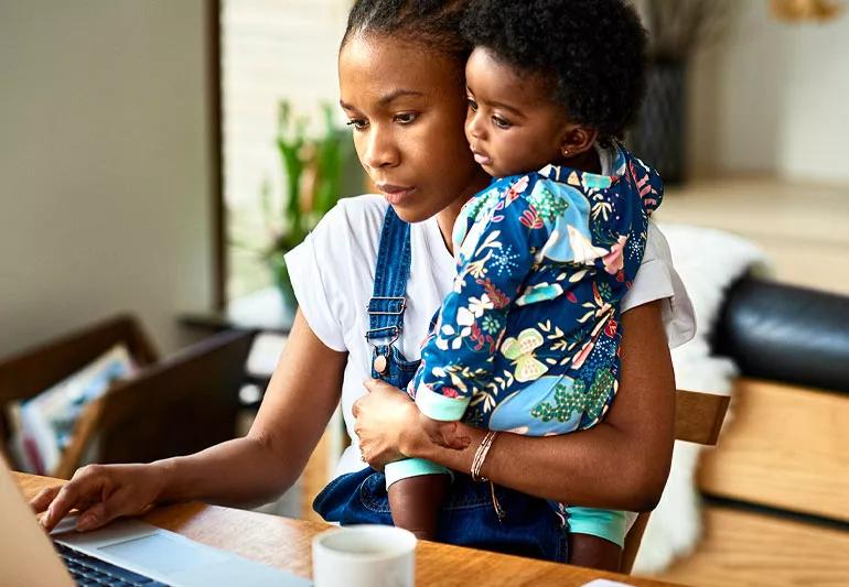 woman holding child while trying to work