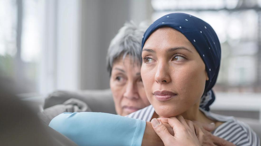 Female wearing bandana on head being embraced by family member