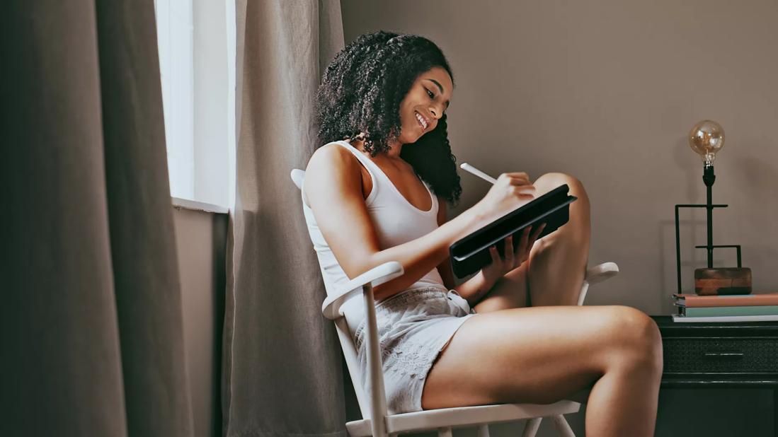 Person sitting in chair writing in tablet