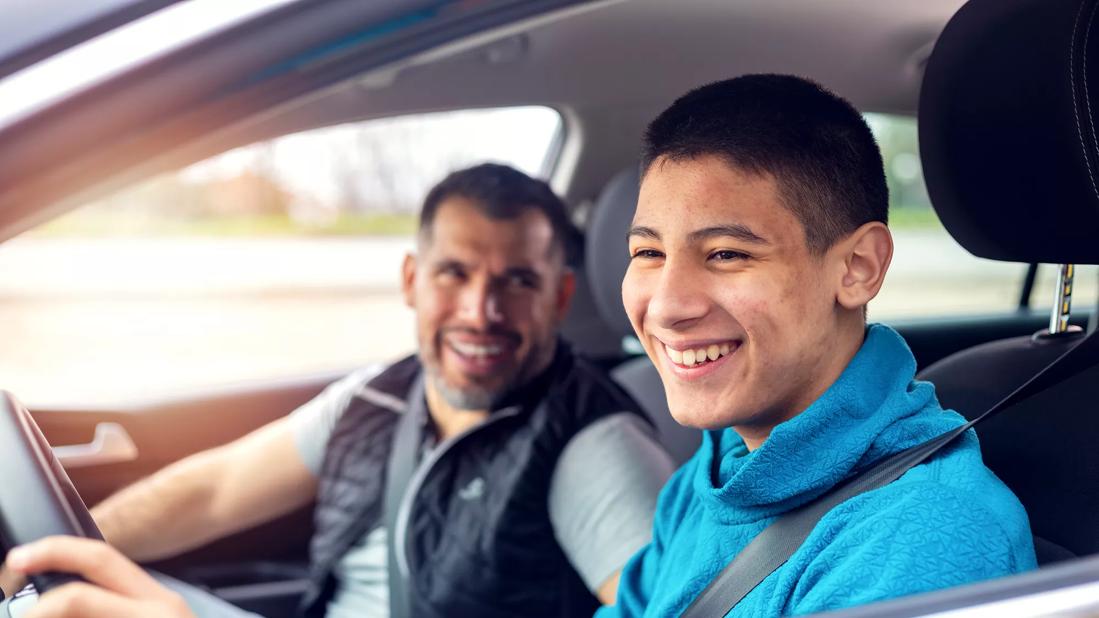 Adult in the passenger seat of car while smiling teen drives