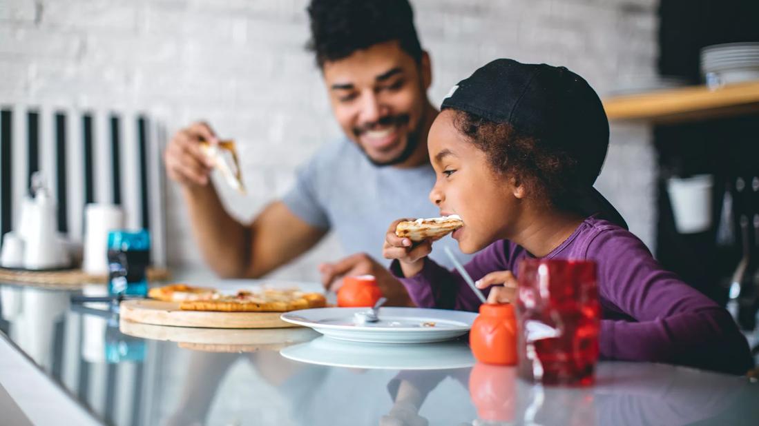 Caregiver and child eating pizza together