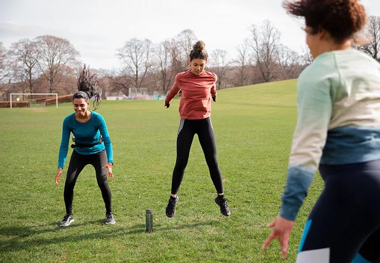 People doing burpees while outside on a grassy field