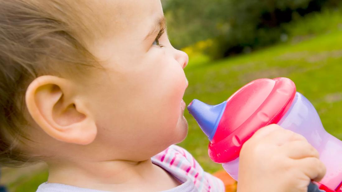 Happy toddler holding sippy cup