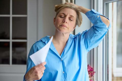 Female holding hair up at neck, eyes closed, fanning herself with piece of paper