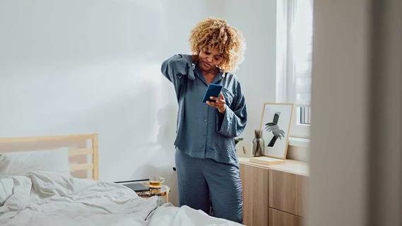 female looking down at smartphone, rubbing back of neck