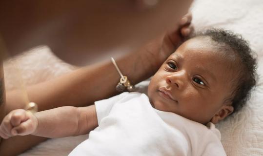 Caregiver leaning over happy baby