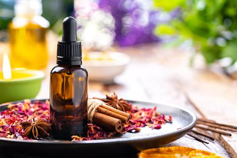 Bottle of essential oil on plate of potpourri, with and candles