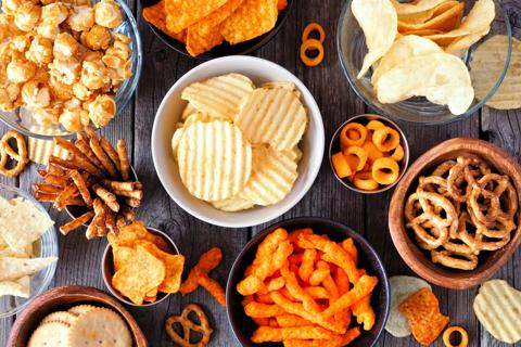 Bowls of processed snacks, potato chips, carmel corn, pretzels, cheese puffs