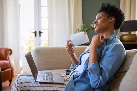 Female sitting on couch at home fanning their face from hot flash