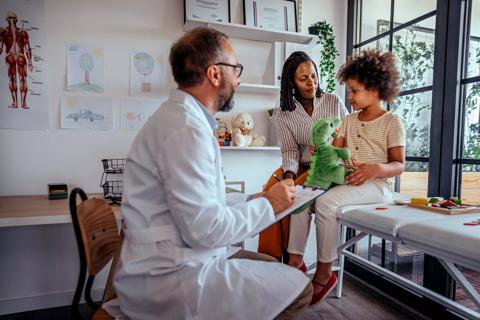 Caregiver and child with doctor in kid-friendly pediatrician office