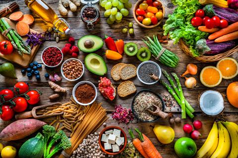 Table of assorted healthy foods, like fruits, veggies, grains, nuts and olive oil