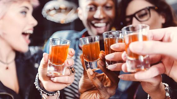 Closeup of people holding up shot glasses