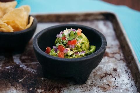 Motar of mediterranean guacamole, with motar of corn chips nearby