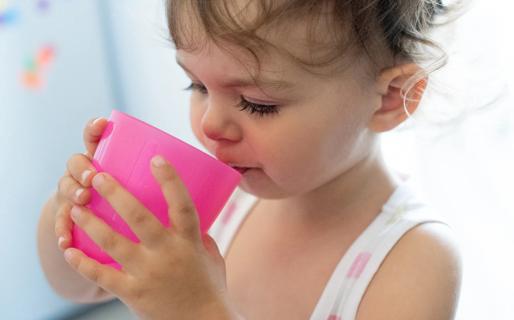 Toddler drinking from a pink cup