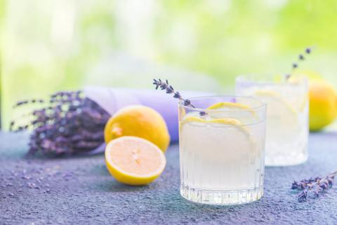 Glasses of lemonade with lavendar sprig, ice and lemons, lavendar on the table