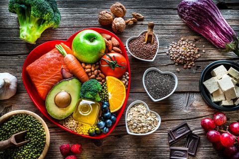 Heart-healthy foods in a heart-shaped dish on wooden table with other heart-shaped filled bowls