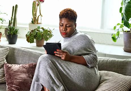 Person relaxing on couch at home, reading on a tablet