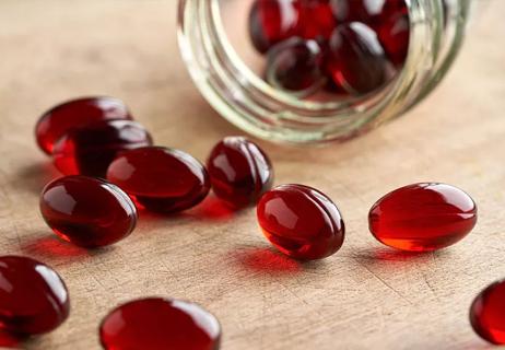 Oval-shaped maroon pills spilling out of a tipped-over glass jar