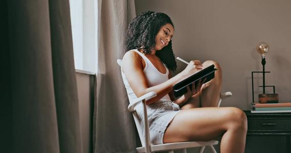 Person sitting in chair writing in tablet