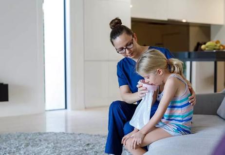 parent comforting child by holding vomit bag