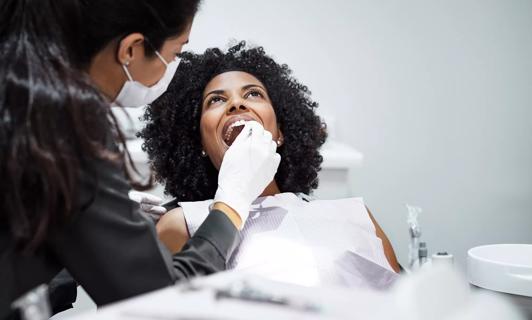 Person in dentist chair getting an exam by a dental provider