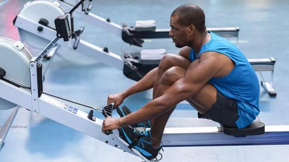 Adult male using rowing machine at gym