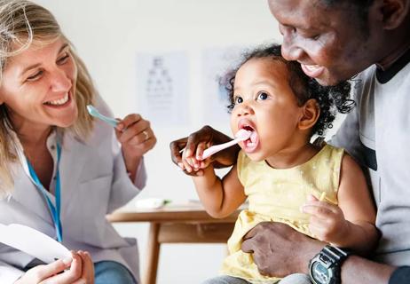 Baby and father with dentist learning about tooth care