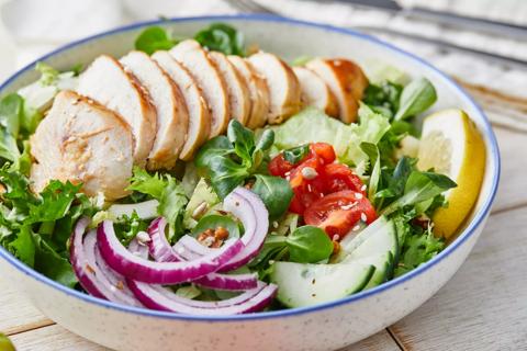 Sliced grilled chicken over salad