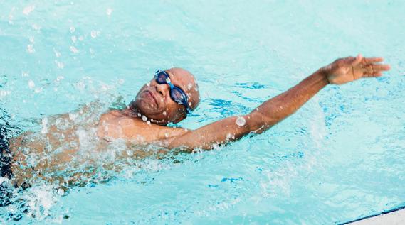 Person wearing goggles doing the back stroke in a pool