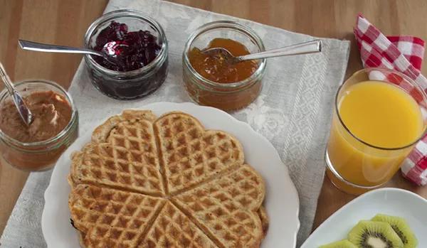 Plain whole-grain waffle with jellies and peanut butter for toppings, with glass of OJ