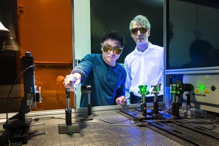 Jian Chen (left) and Adrian Sabau (right) work with a laser to prepare a carbon fiber composite surface for joining with aluminum